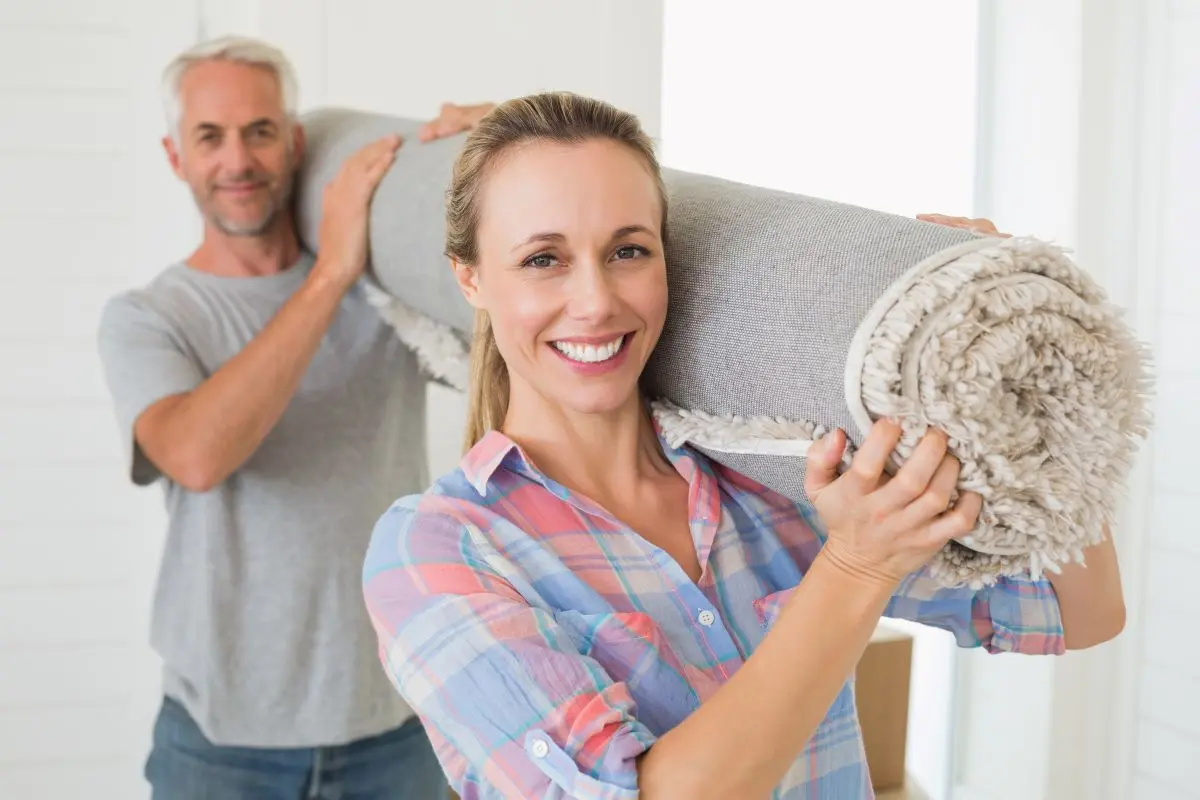 Happy couple carrying a rolled up rug together