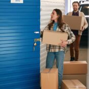 Young woman and man putting big cardboard boxes into their storage unit.