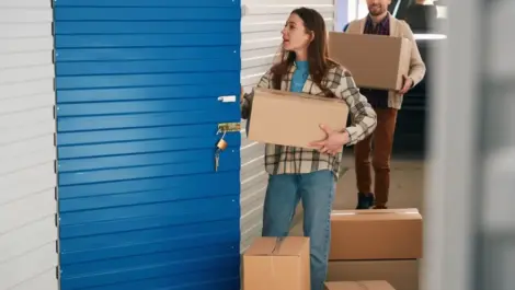 Young woman and man putting big cardboard boxes into their storage unit.