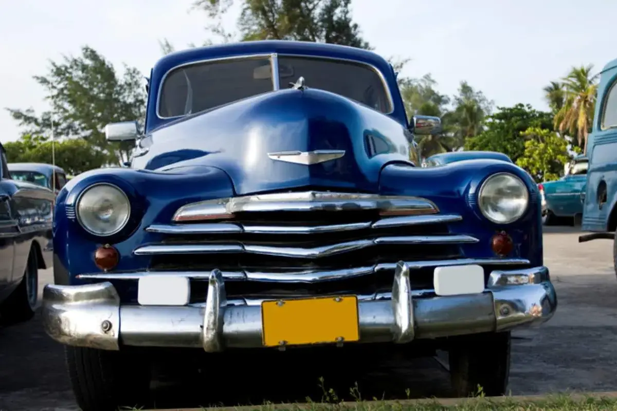 A blue antique car parked in the sunshine.