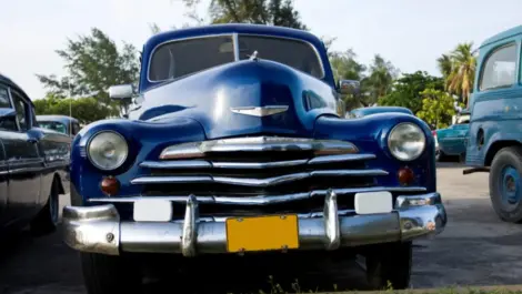 A blue antique car parked in the sunshine.