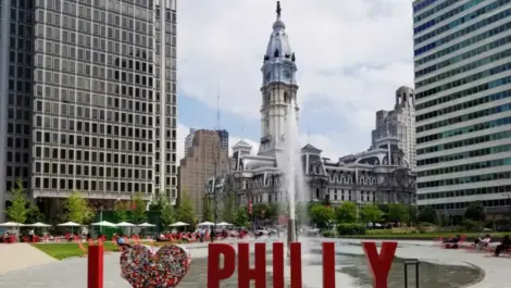 I Heart Philly sign with City Hall in the background at the corner of Market St and Broad St downtown Philly