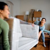 Happy women carrying sofa into their new apartment