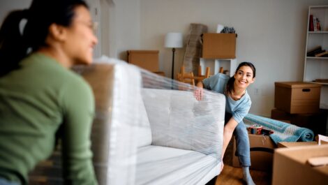 Happy women carrying sofa into their new apartment