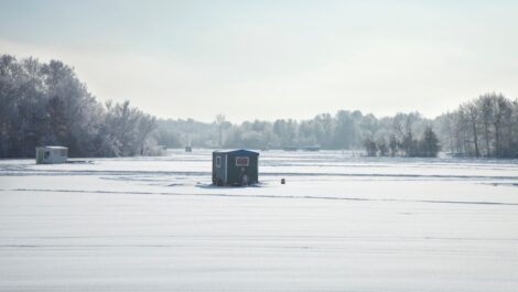 Ice fishing shelters at a Minnesota lake during a bright winter morning.