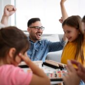 : A young family plays a board game surrounding a table