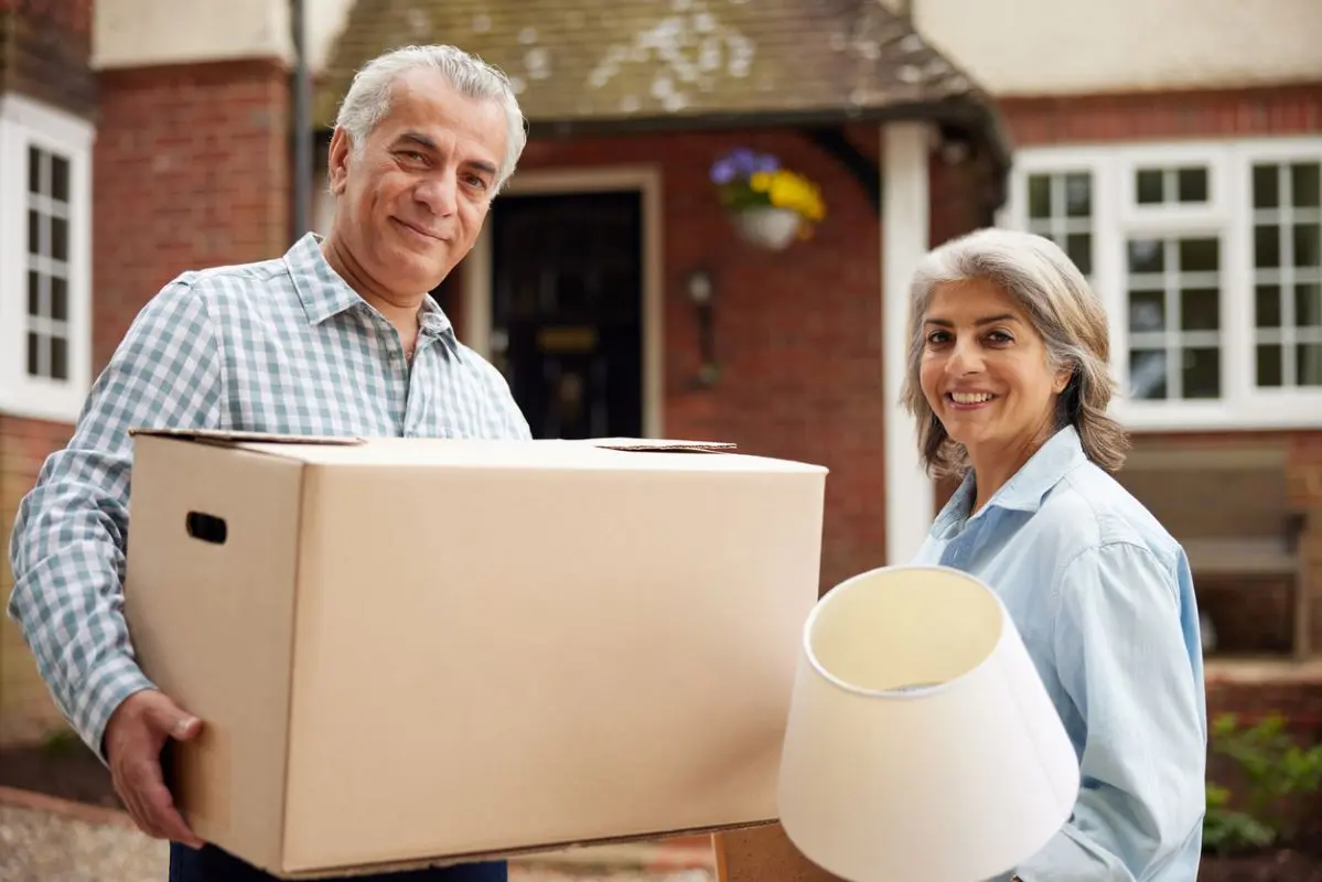 Older couple moving boxes into a storage unit as they are downsizing.