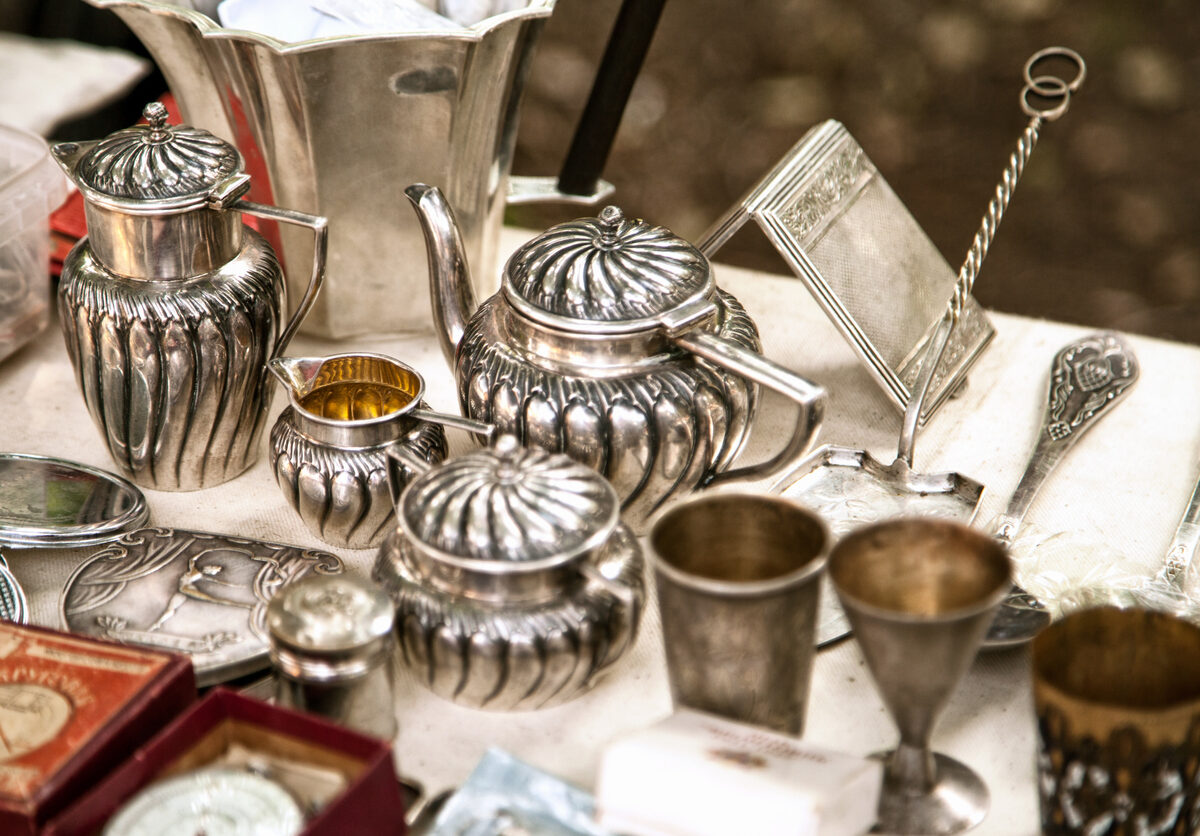 Silver cups and teapots sit on a table.