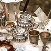 Silver cups and teapots sit on a table.