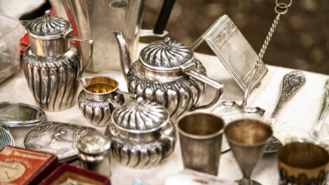 Silver cups and teapots sit on a table.