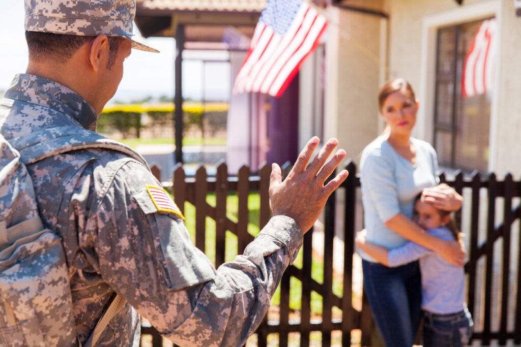 A soldier waves goodbye to his wife and daughter.