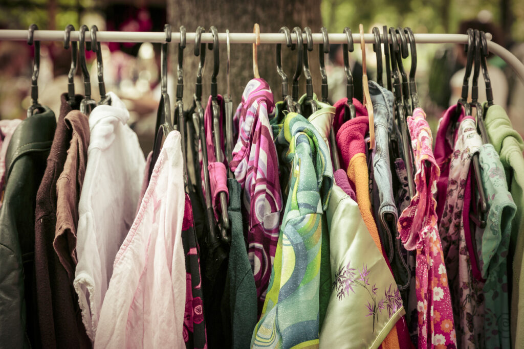 A clothing rack with various colorful shirts and jackets hanging on it. 