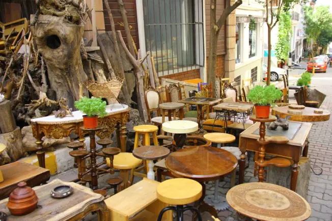 A flea market filled with secondhand furniture, including tables, stools, and plant stands. 